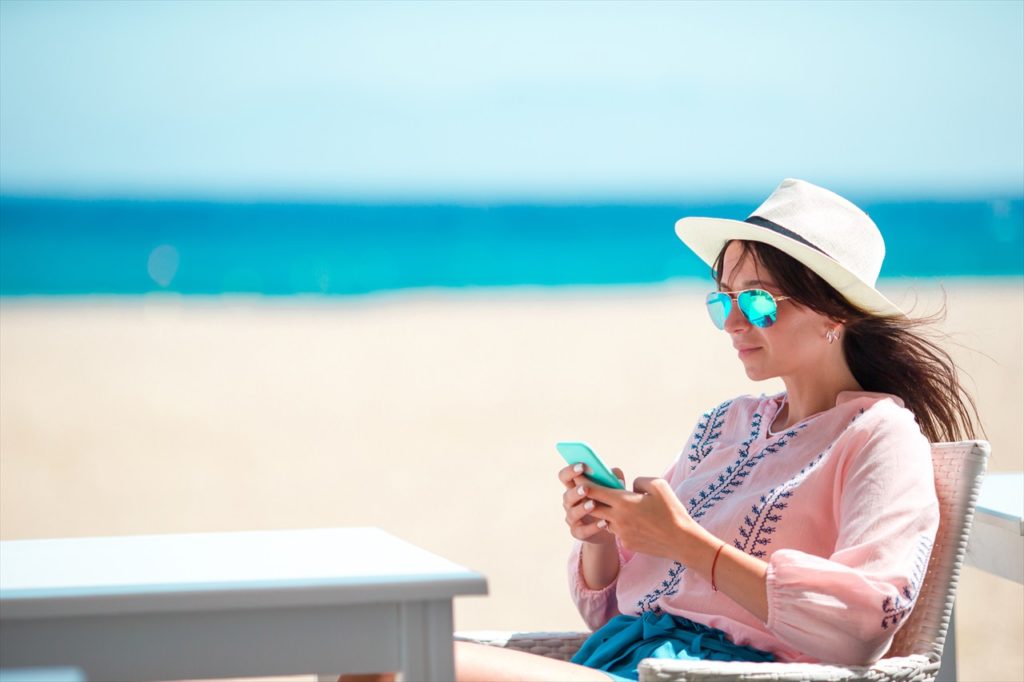 海でスマホを操作する女性